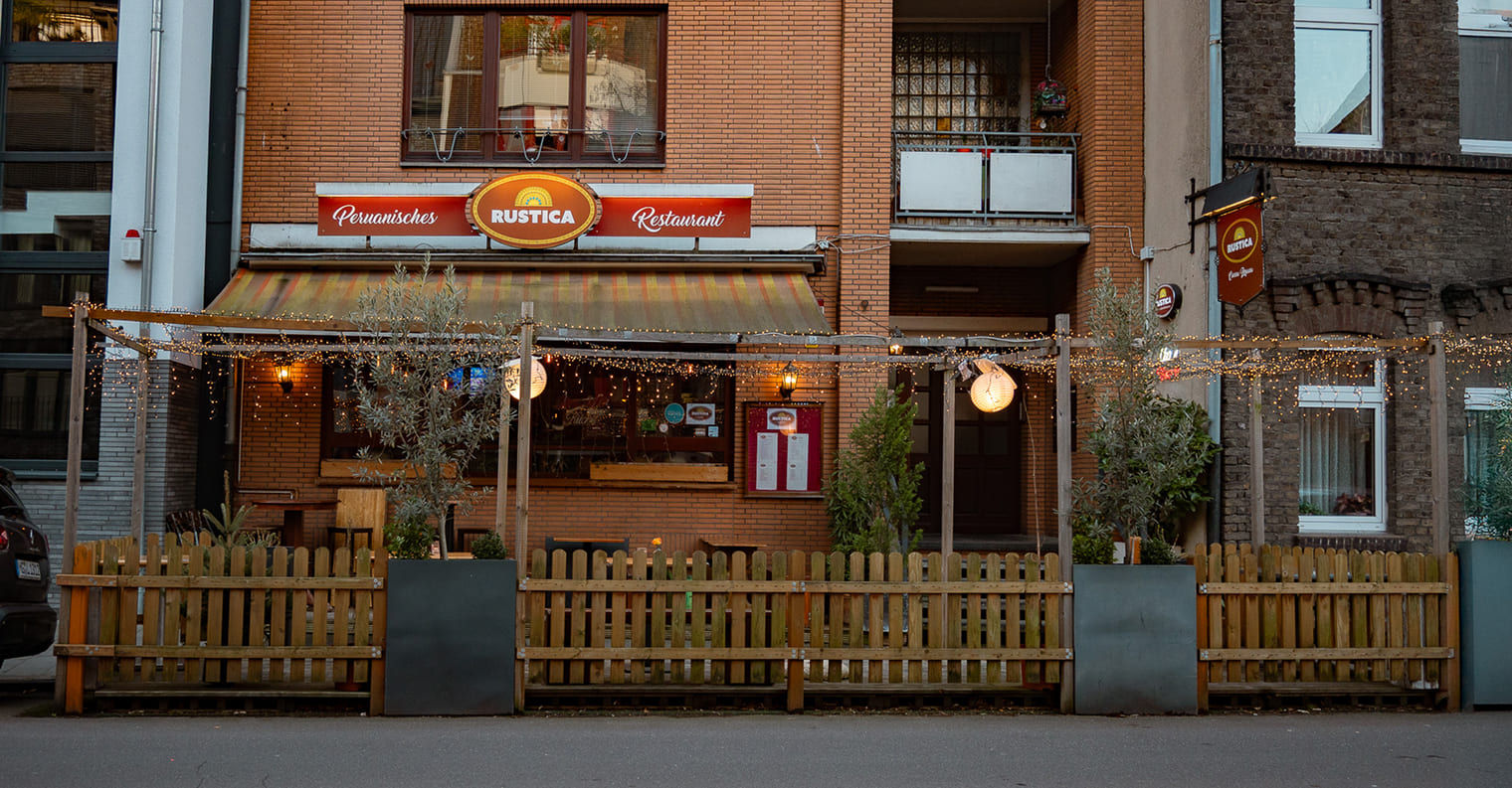 Außenansicht des Rustica – Peruanisches Restaurant in Düsseldorf mit beleuchteter Terrasse
